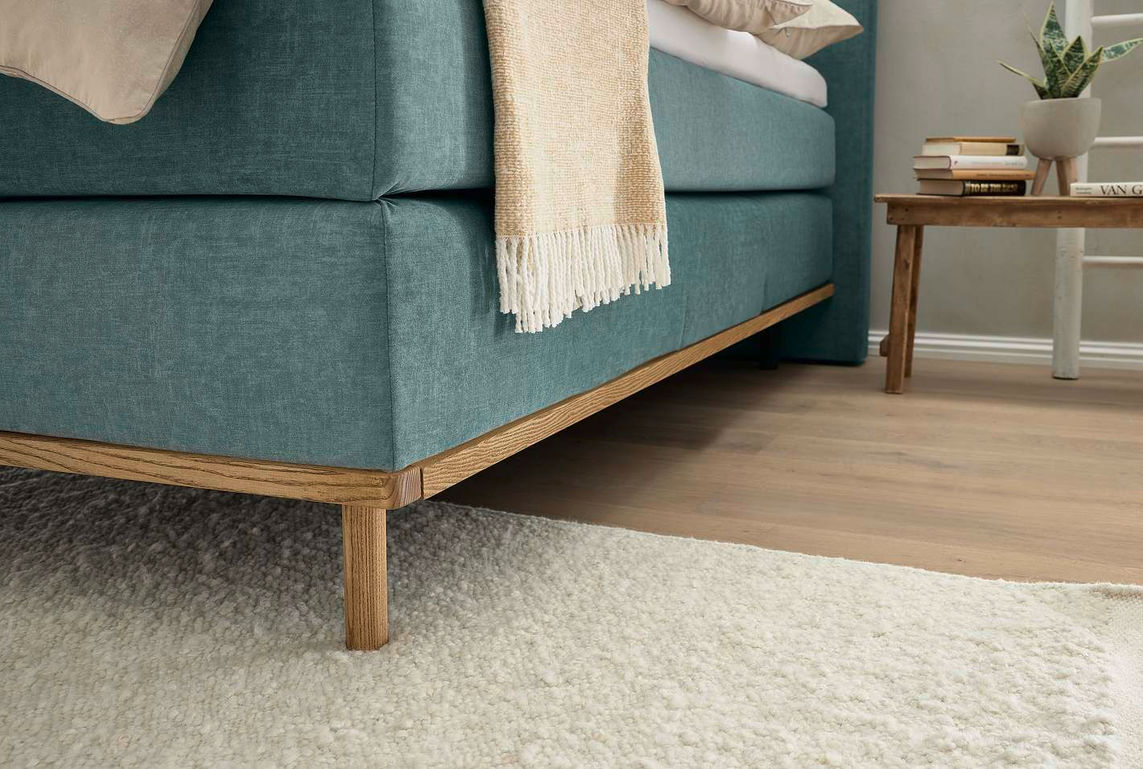 Boxspring — бирюзовая кровать с деревянным основанием на светлом ковре